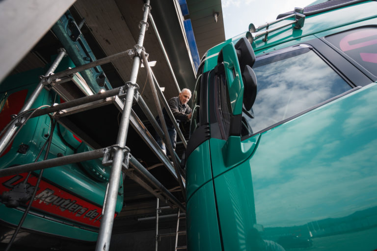 Un mécanicien sur un échafaudage en train de refaire le haut de la carrosserie d'un poids lourd.